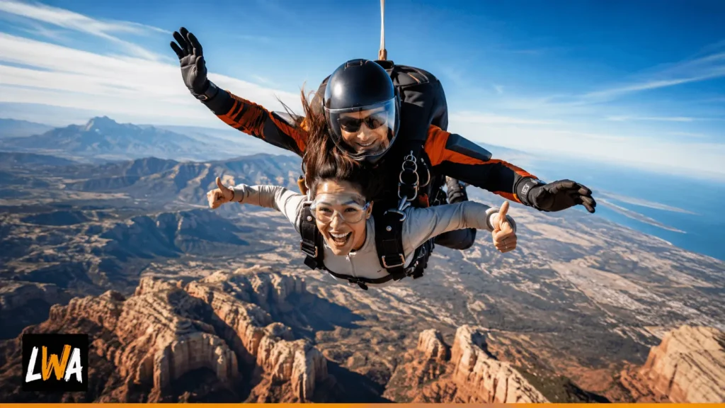 First-time tandem skydiver in freefall above red-rock desert, mountains and a distant coastline in the United States.