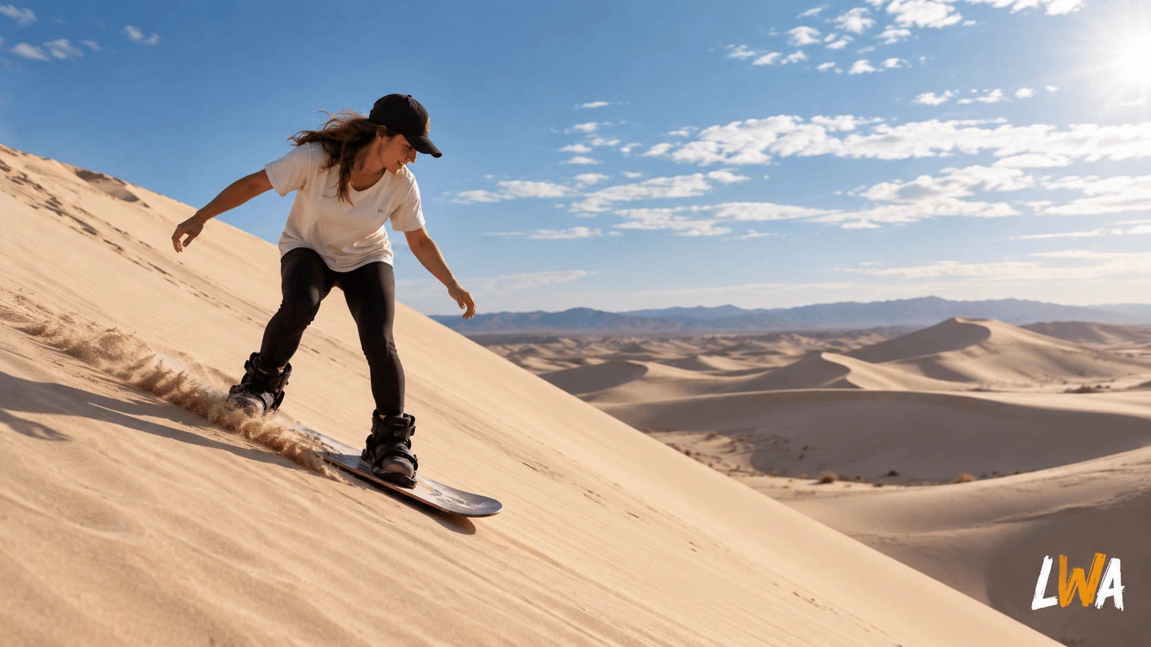 Beginner riding a sandboard down a large U.S. sand dune